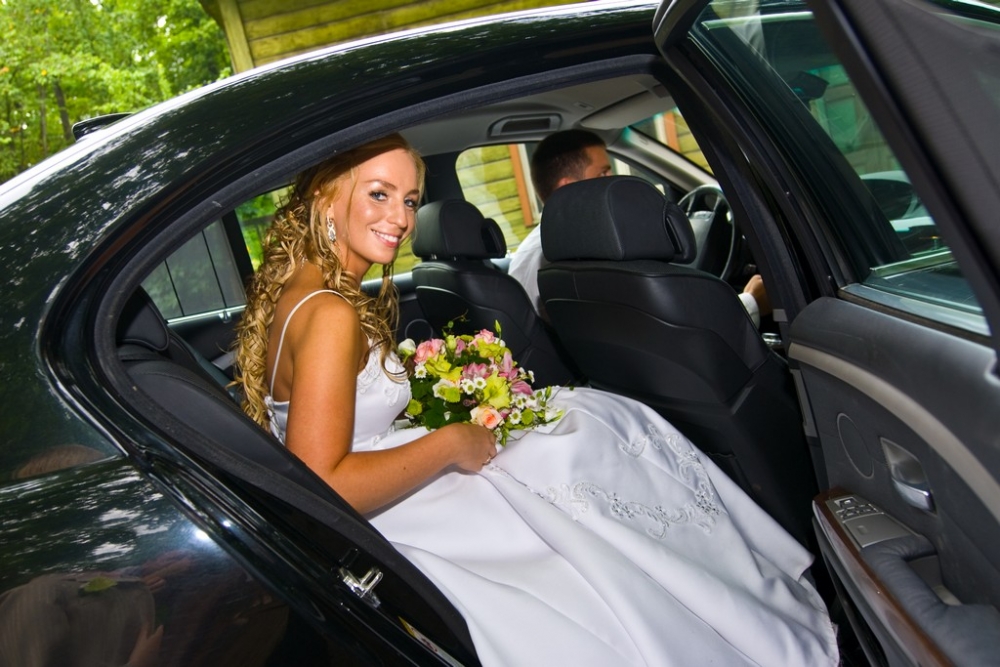 Bride sitting in a black wedding limousine.